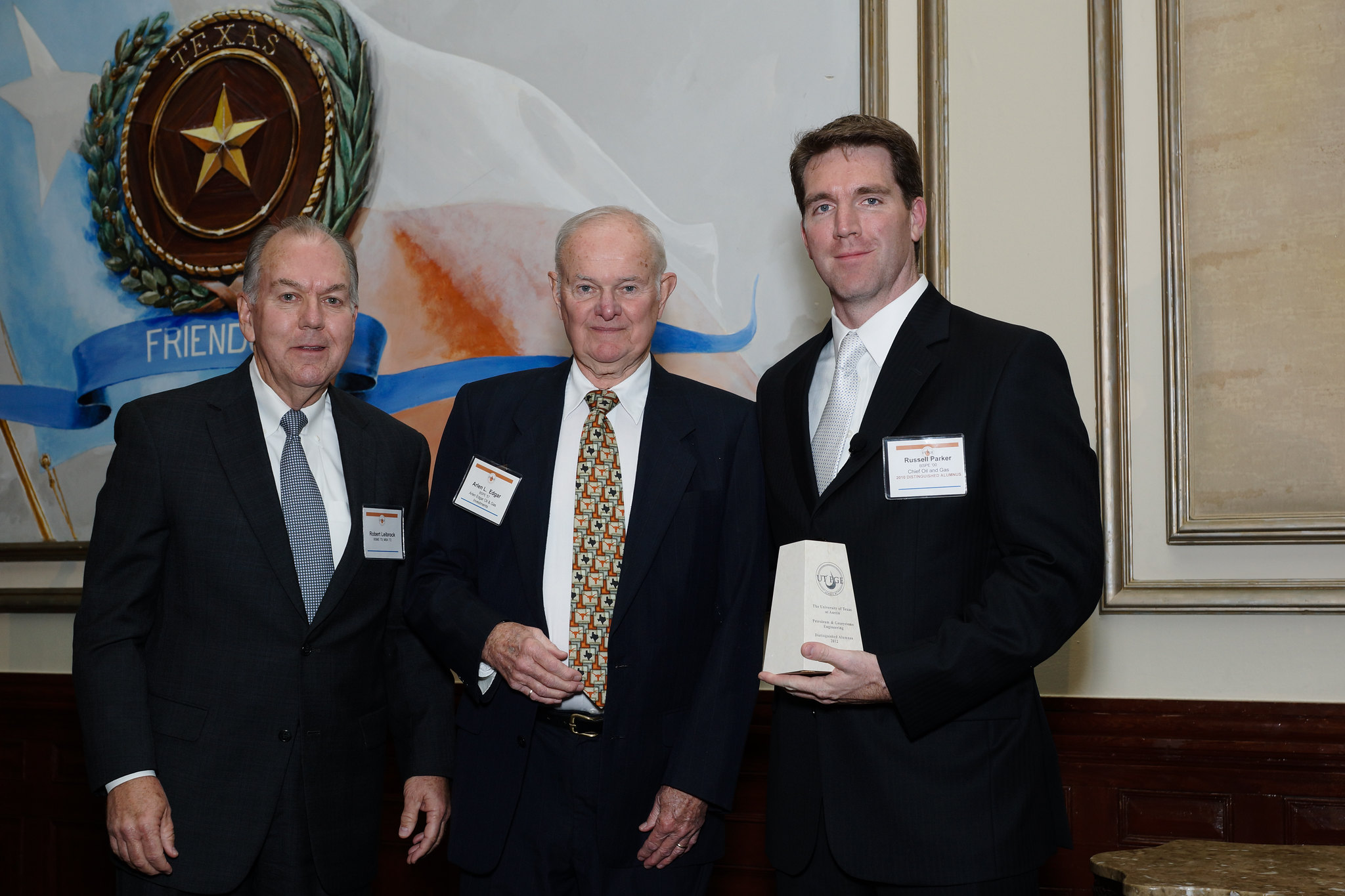 Distinguished alumni award recipients holding their awards and smiling.