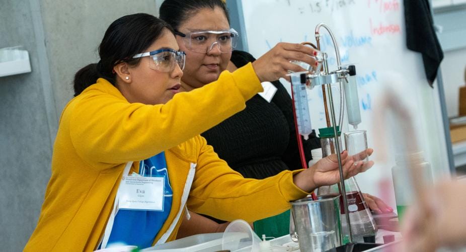 ESTI participants wearing safety goggles while touching lab equipment.