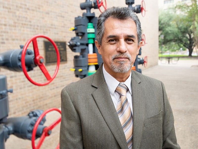 Alberto Lopez-Manriquez smiling in front of valve controls attached to building exterior.
