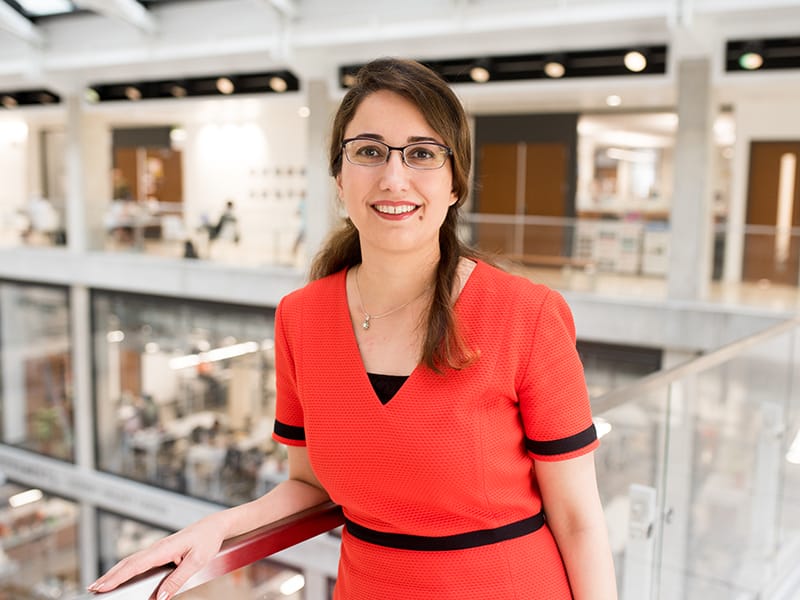 Zoya Heidari smiling and holding railing in EER building on UT Austin campus.