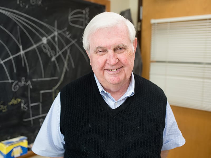Larry Lake smiling in front of blackboard.