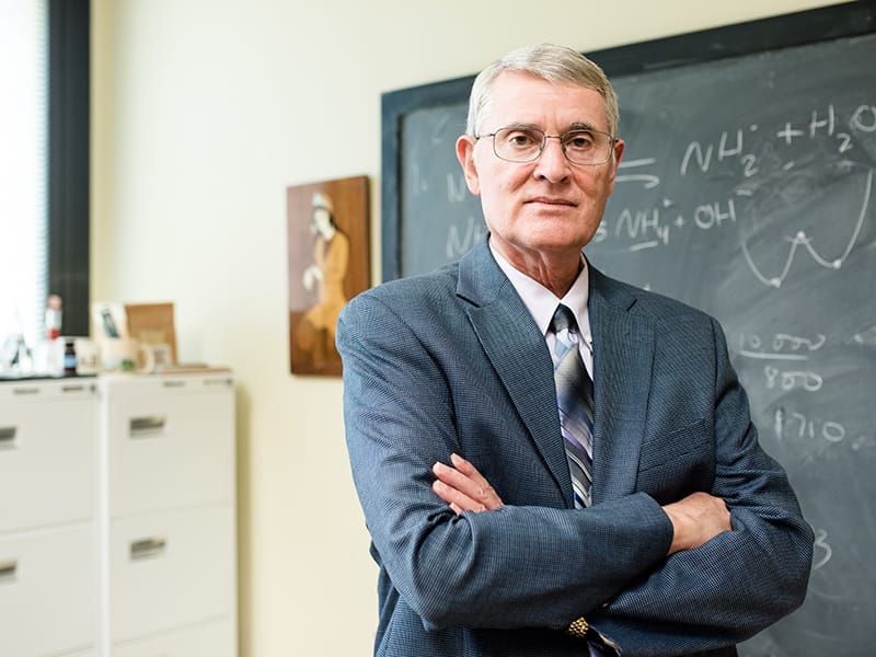 Gary Pope standing in front of chalkboard in classroom with his arms crossed.