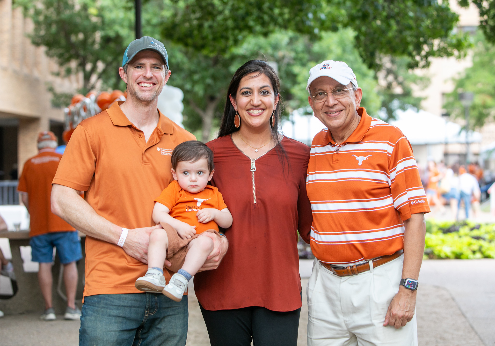 Professor Mukul Sharma smiling with UT PGE alumni while wearing UT Austin hate and shirt.