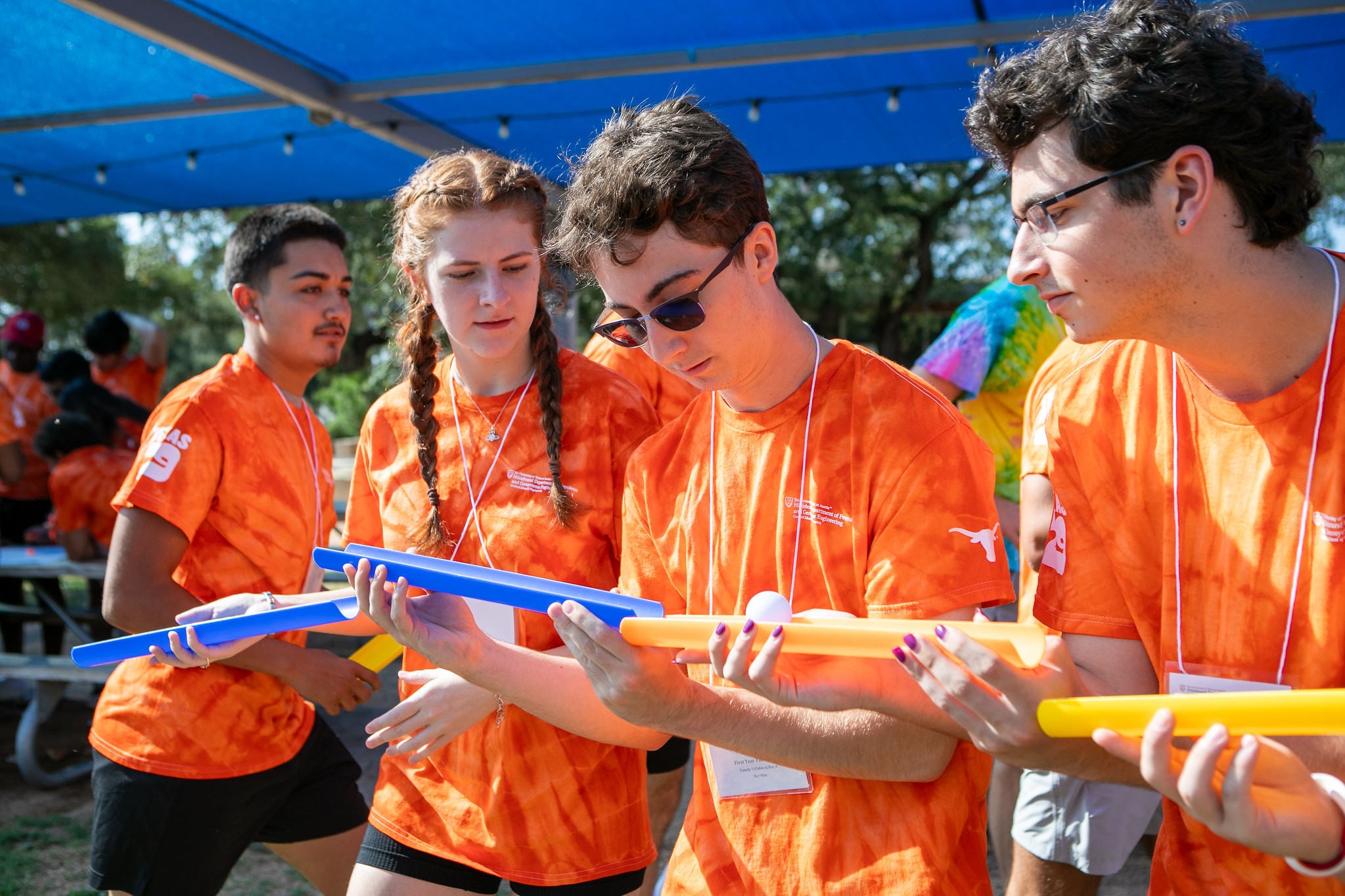 PGE students wearing PGE t-shirts working together to guide ball using tubes.