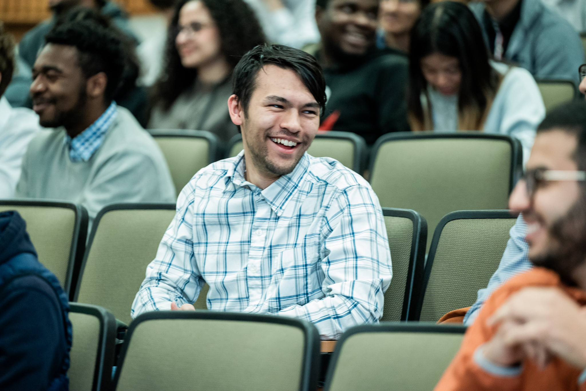 PGE students laughing in auditorium during presentation.