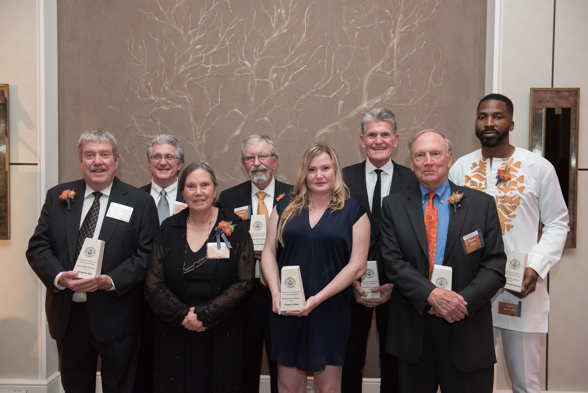 Distinguished alumni award recipients holding their awards and smiling.