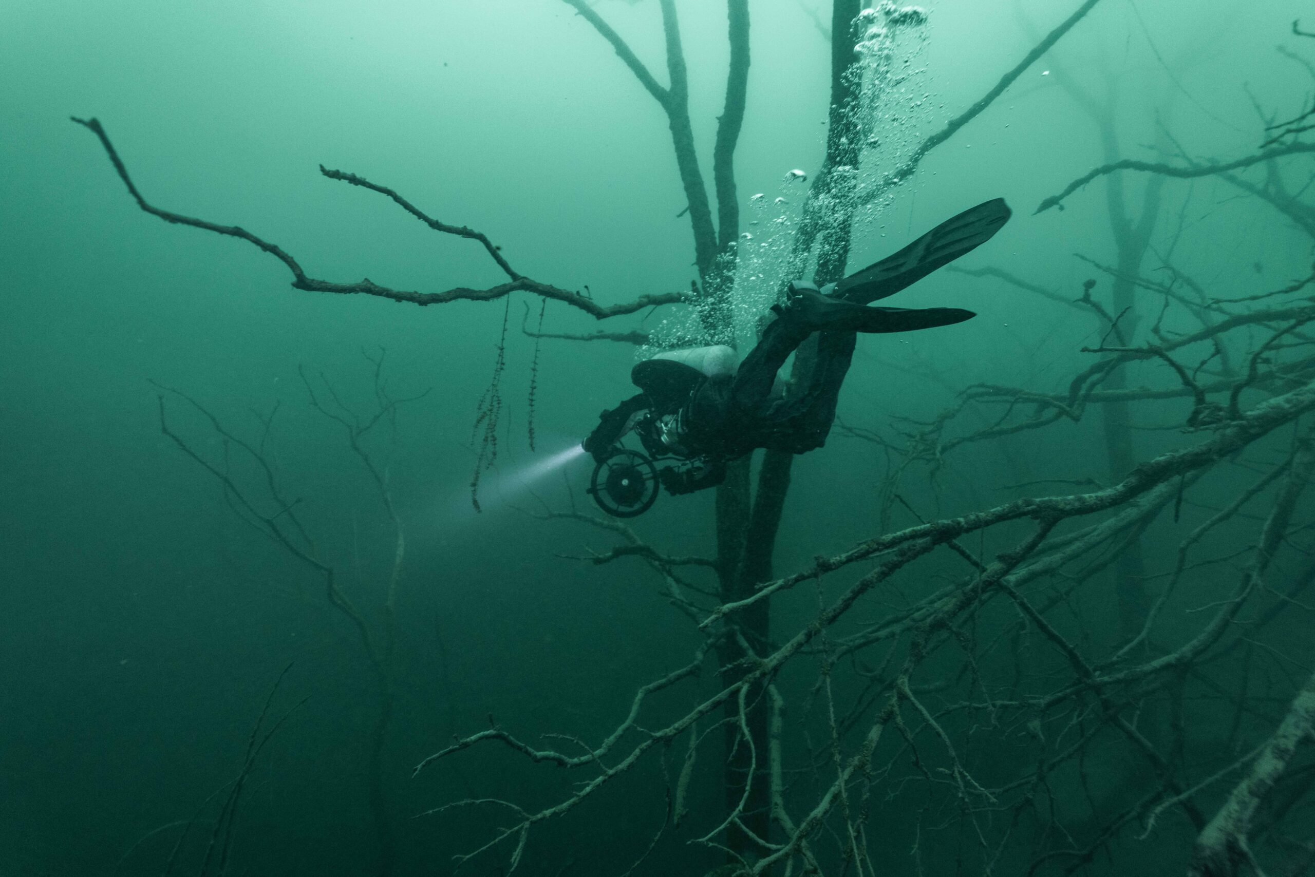 Underwater photo of scuba diver swimming next to debris.
