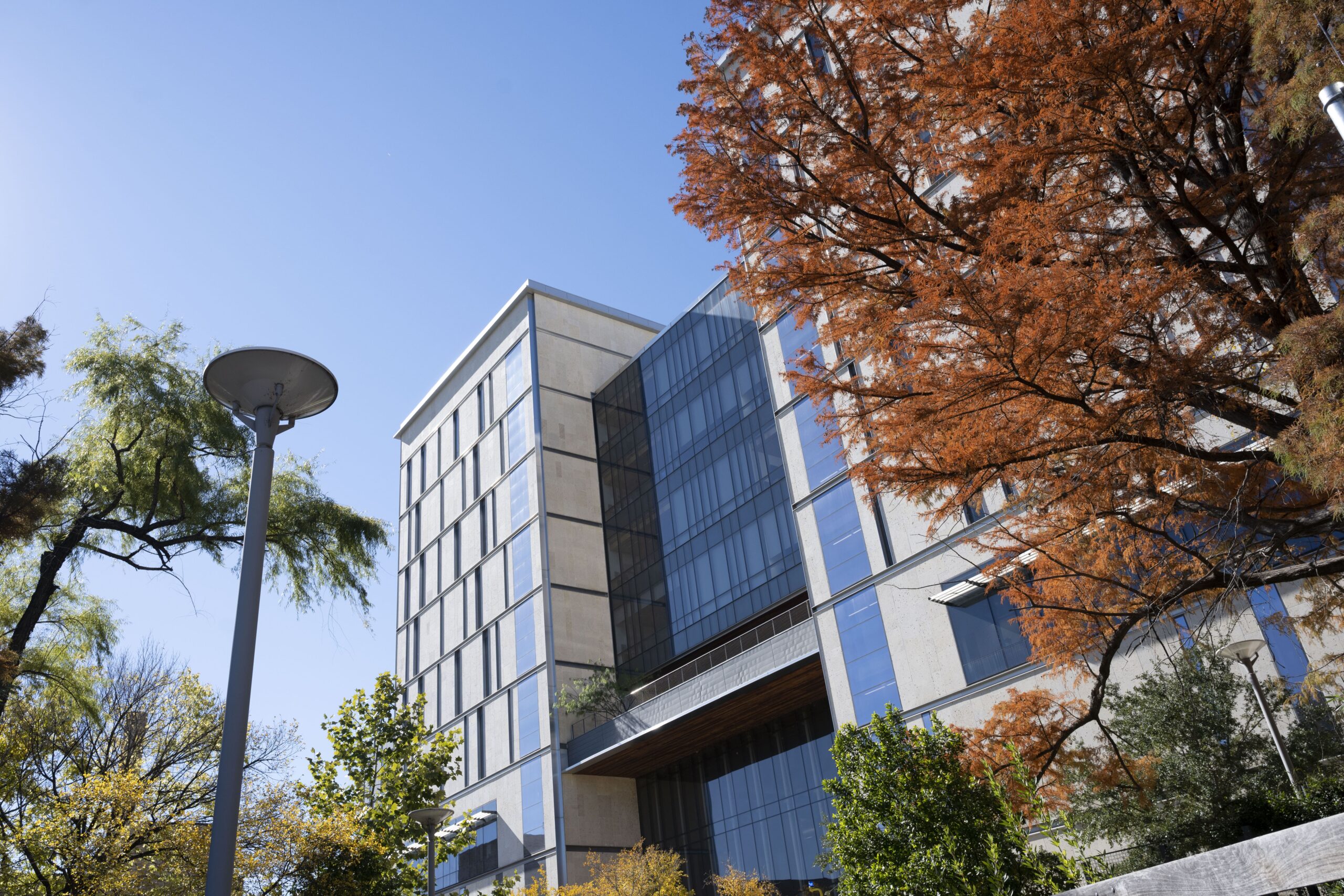 Exterior of EER Building on UT Austin campus with leaves turning orange during fall.