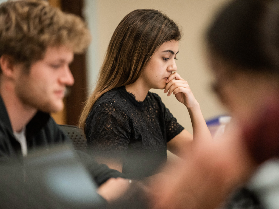 Students sitting at tables together looking at laptop screens.