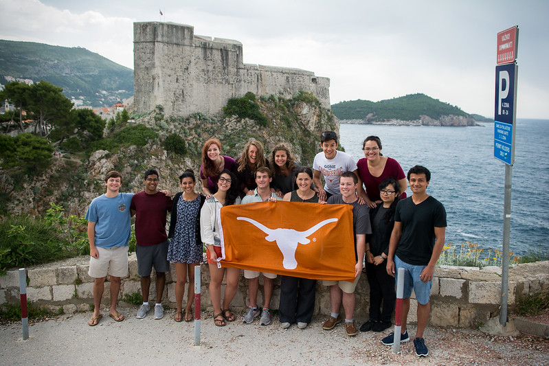 UT PGE students pose with Longhorn flag in front of ancient ruins